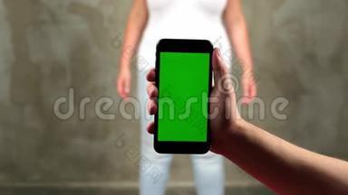 男人`手拿着一部带有垂直绿色屏幕的移动电话，这是有轨电车色度关键智能手机技术手机
